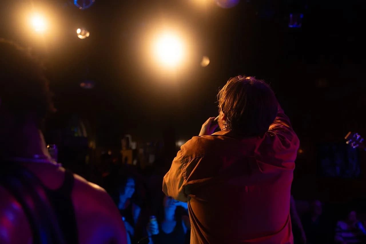 Mike Starr — concert, singer, audience, stage, spotlight, orange, show, room, live music, entertainment, fans, atmosphere, music, microphone, energy, evening, podium, artist, performance, party, club