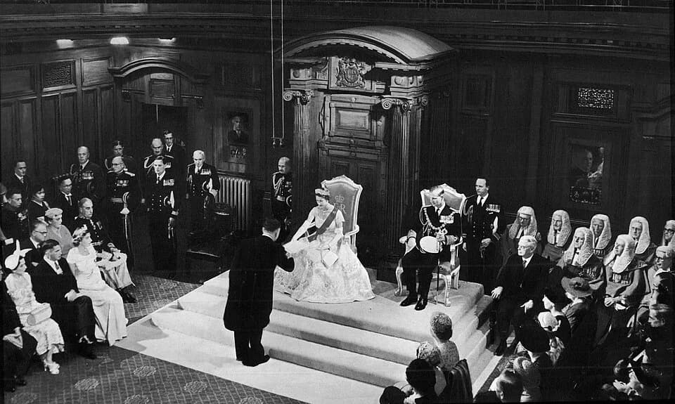 Elizabeth II - Her Majesty Queen Elizabeth II opening a session of the New Zealand Parliament on 12 January 1954 in the Legislative Council Chamber, Parliament House. She is accepting a vellum copy of