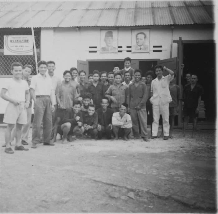 Sukarno Sukarno - Foto. Groepsportret van werknemers van de NV Enschede / Pelangi in Djakarta, gefotografeerd onder portretten van onder meer president Soekarno