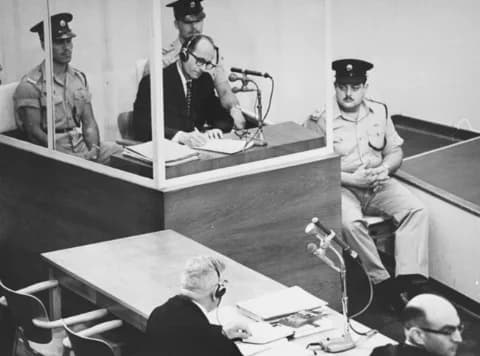 Adolf Eichmann - The Defendant inside his glas booth during the Eichmann Trial in Jerusalem. At the table in the foreground: Defense counsel Robert Servatius (lower center of picture, with headphones)
