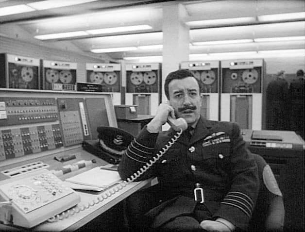 Peter Sellers - Peter Sellers as Group Captain Lionel Mandrake in Stanley Kubrick's 1964 film, Dr. Strangelove. Sellers is sitting at the console of an w:IBM 7090 computer with w:IBM 729 magnetic tape