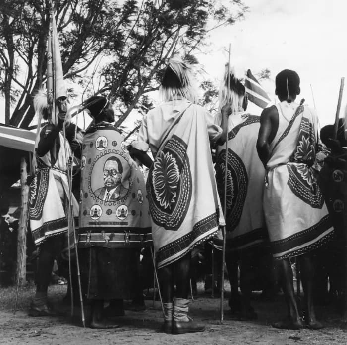 Jomo Kenyatta - De tweede man van rechts draagt een herdenkingsdoek met een afbeelding van de Keniaanse president Jomo Kenyatta (20-10-1893 - 22-8-1978). In 1963 won Kenyatta met zijn partij de Kenya 