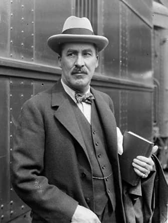 Howard Carter - Informal portrait of Howard Carter (the archaeologist) standing with a book in his hand next to a train at a station in Chicago, Illinois.