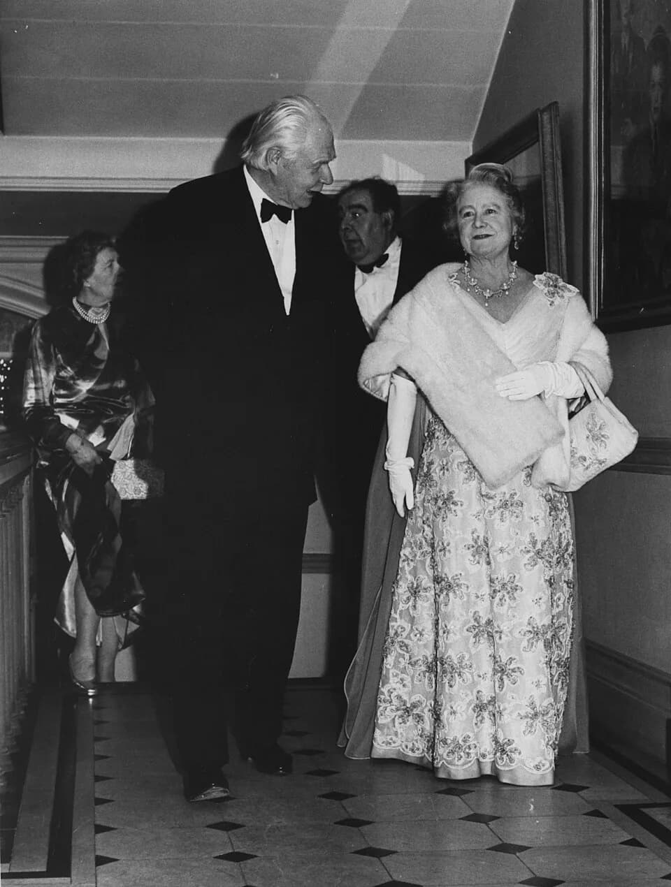 Queen Elizabeth the Queen Mother - 19th February, 1974. Front: Lord Robbins and HM Queen Mother, Back: Lady E. Bassett (Lady in waiting), Lord Goodman.  Taken by Derek Summers.
IMAGELIBRARY/626

Persi