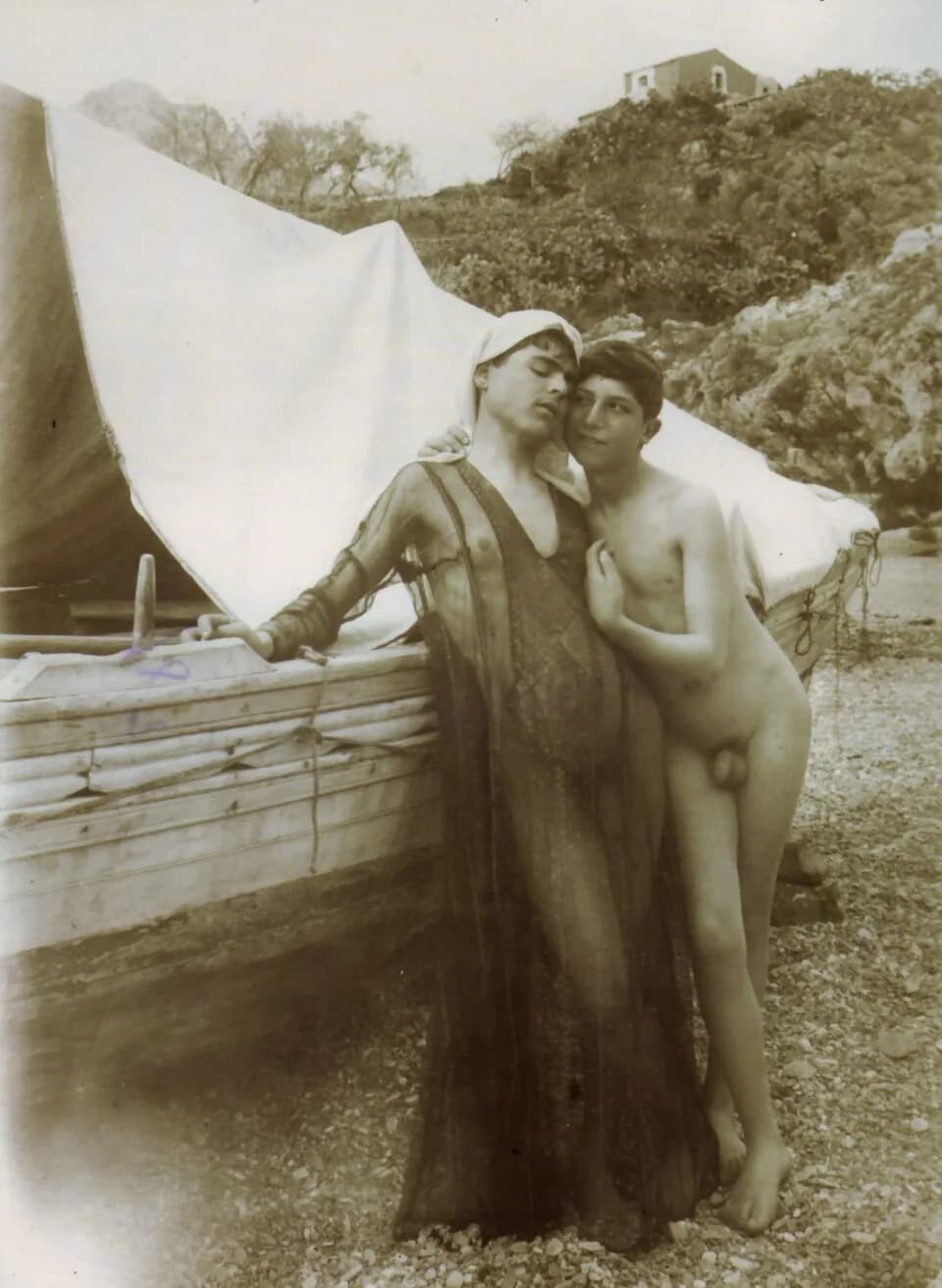 Roland Barthes - Wilhelm von Gloeden (1856-1931). Two boys hugging, one of them wearing a see-through garment, by a boat. Catalogue number: 1428. Cm 18x24.