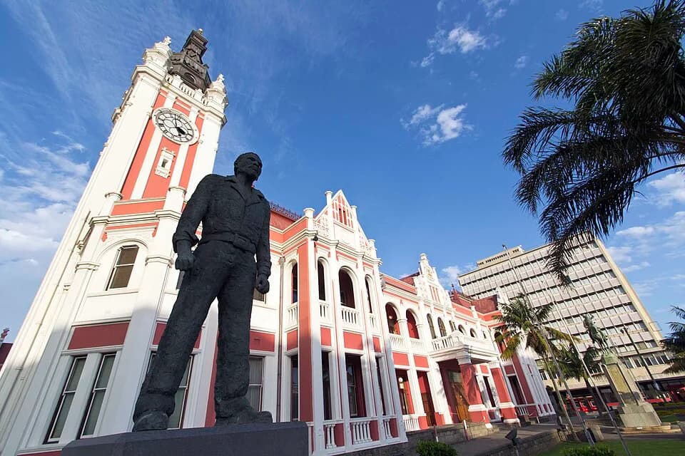 Steve Biko - Victorian, neo-classical and Renaissance features, form an integral part of the historical and architectural core of East London. This view shows the memorial to Steve Biko in the foregro