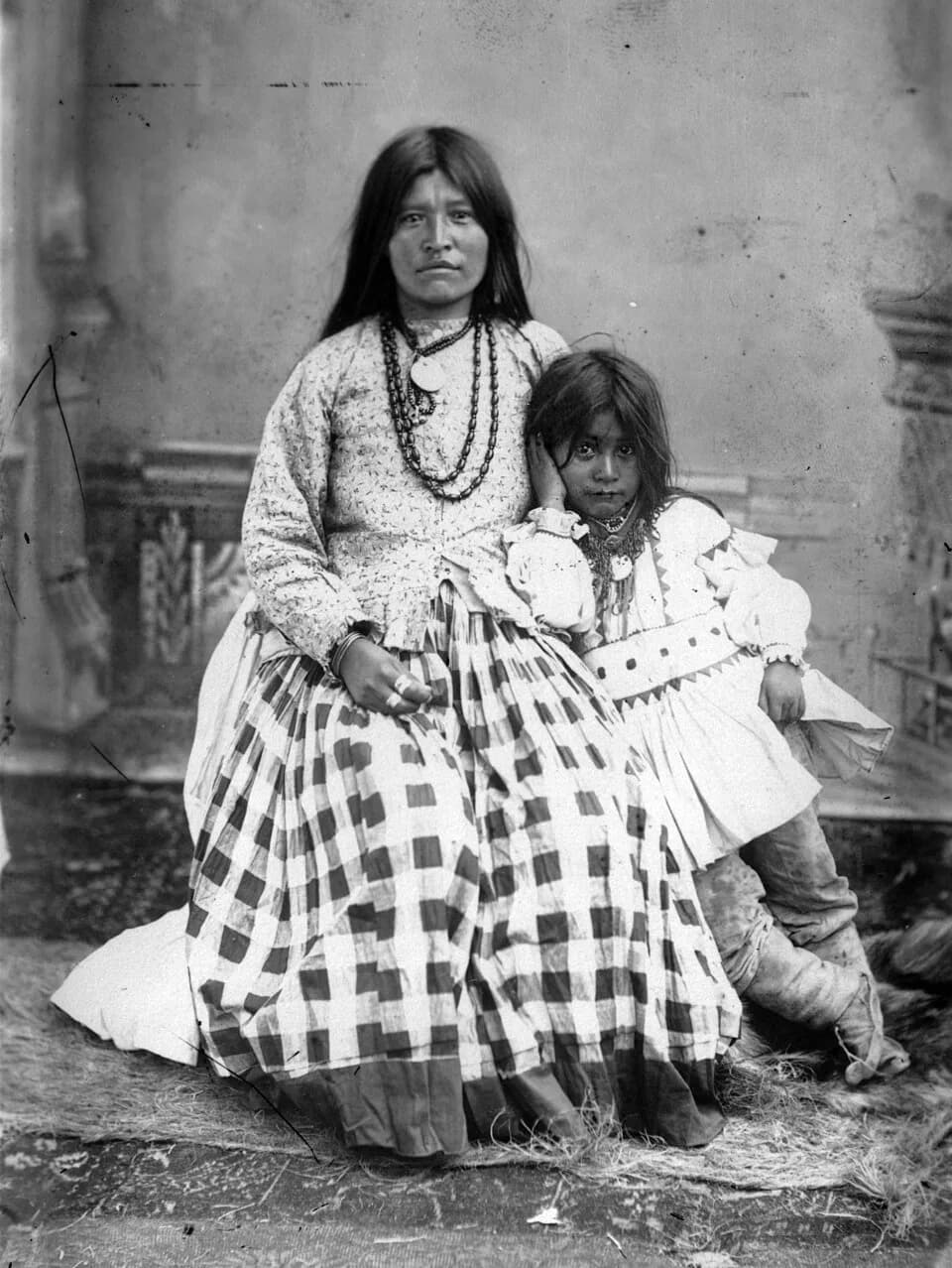 Gerónimo Gerónimo - Studio portrait (sitting and standing) of Ta-ayz-slath (Early Morning), Geronimo's wife, and his son, Native American (Chiricahua Apache) woman and boy. She wears beaded necklaces.