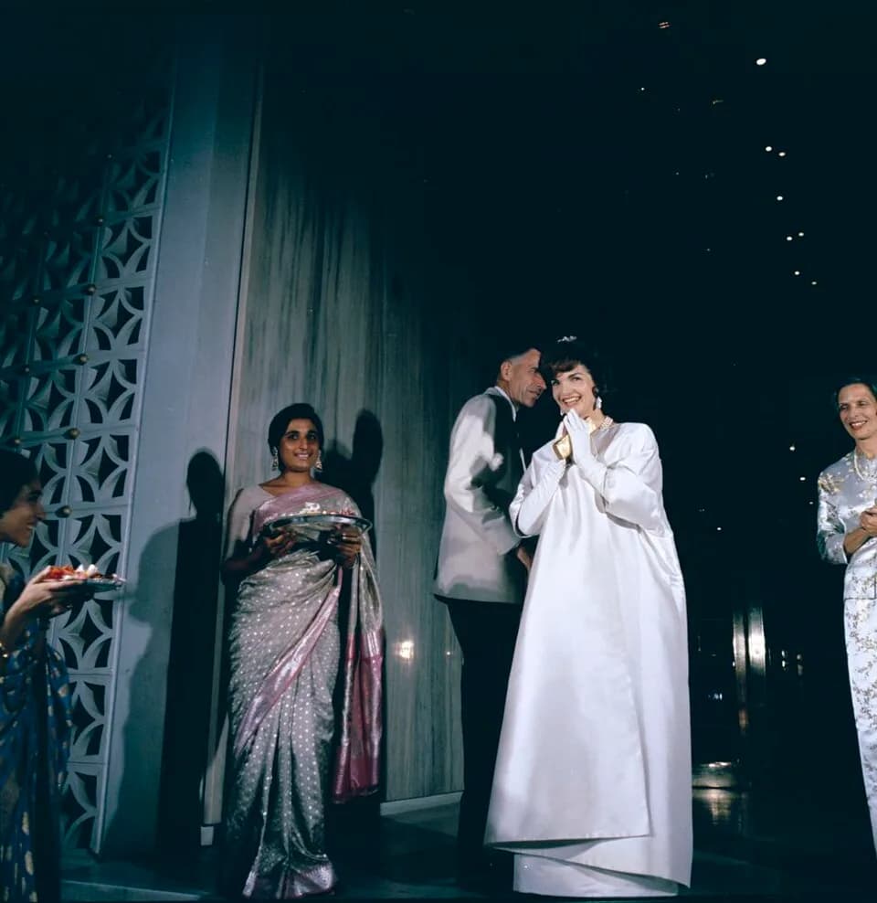 John Kenneth Galbraith - First Lady Jacqueline Kennedy attends a reception at the United States Embassy in New Delhi, India. United States Ambassador to India, John Kenneth Galbraith, stands behind Mr