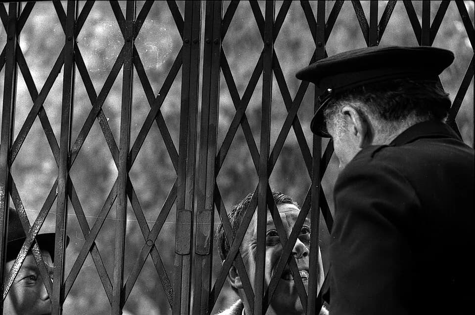 Fernandel Fernandel - Quartier Saint-Sernin. Le 2 novembre 1965. Gros plan sur la grille refermée par un gardien (un acteur) regardant au travers l'acteur Fernandel, lors du tournage du film "La bours