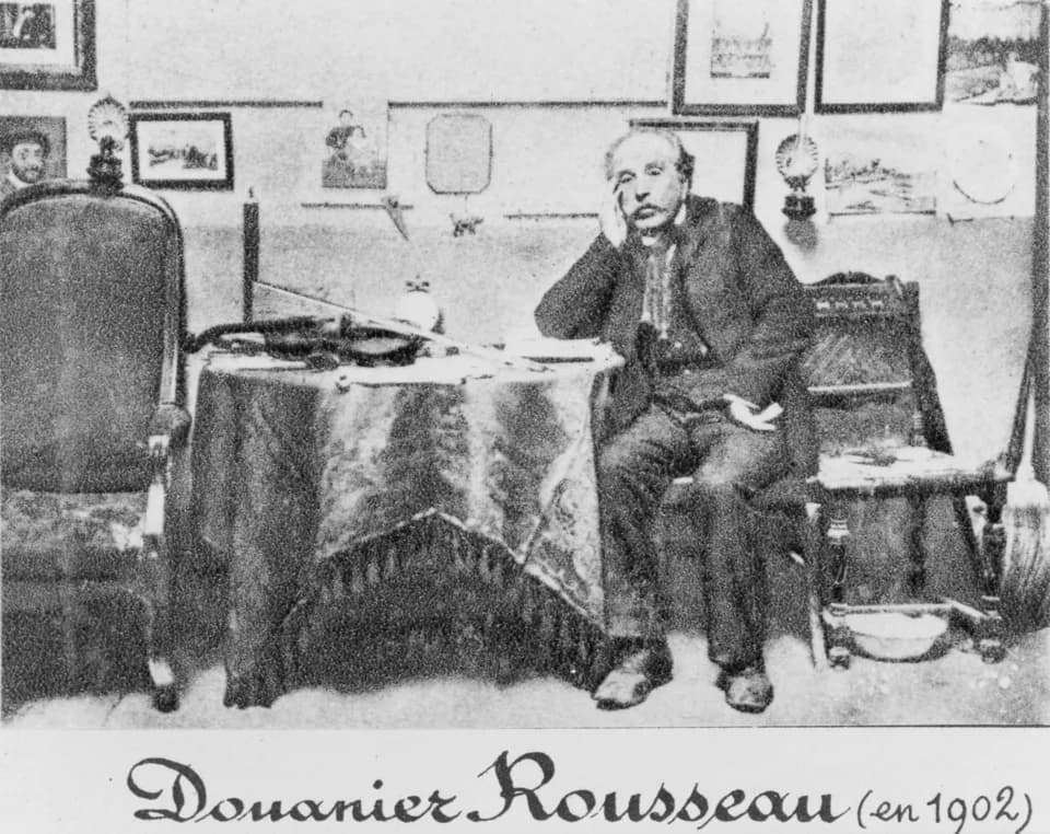 Henri Rousseau - Douanier Rousseau (in 1902). Henri Rousseau, full-length portrait, seated at table, facing front.