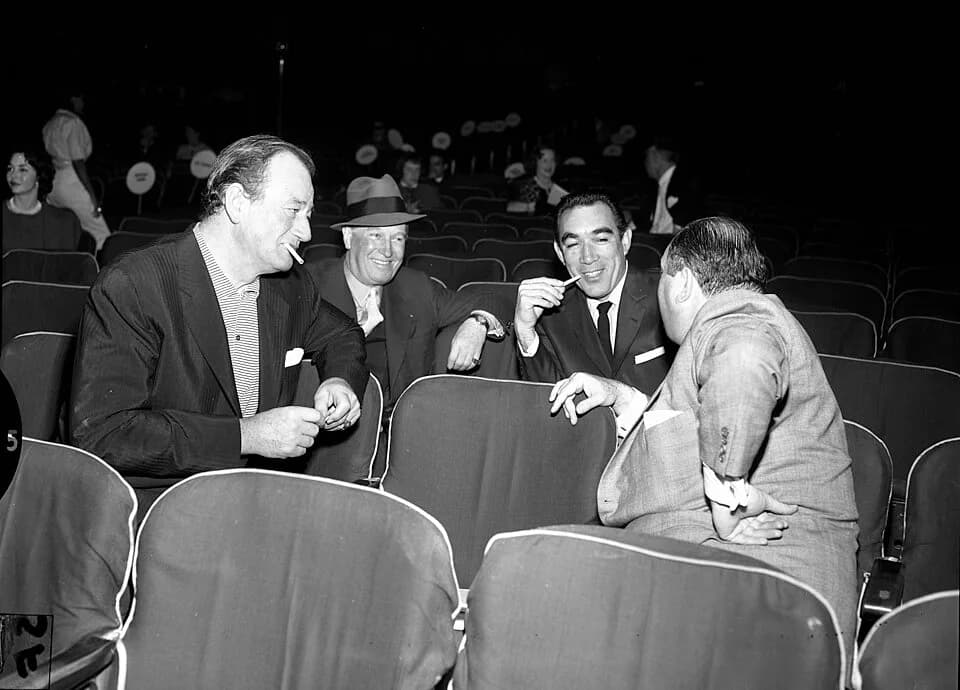 Maurice Chevalier - John Wayne, Maurice Chevalier, Anthony Quinn and Jerry Wald chatting during the 1958 Academy Awards rehearsals. Published caption: TAKING A BREAK-- Getting together for a chat duri