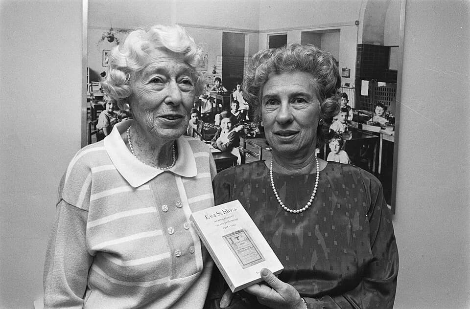 Eva Schloss - Collectie / Archief : Fotocollectie Anefo
Reportage / Serie : [ onbekend ]
Beschrijving : Eva Schloss presenteert het boekje "Herinneringen van een joods meisje", links haar moeder Fritz