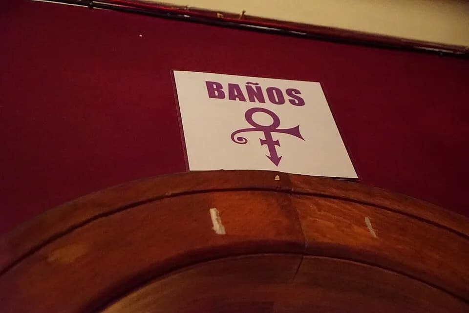 Prince - A purple sign of a unisex bathroom hung above a door at the American Legion in Colonia Roma in Mexico City.
Uses the "artist formerly known as Prince" symbol...