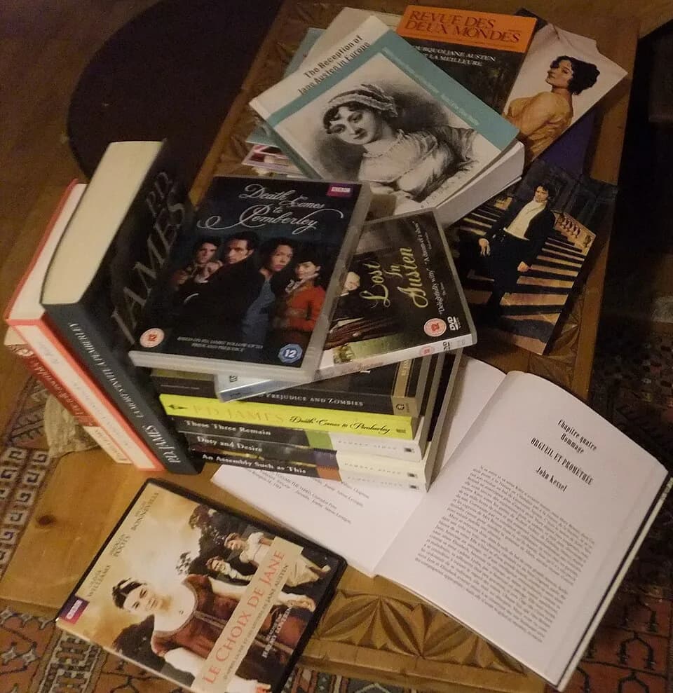 Jane Austen - Empilement de livres variés, en anglais et en français, dérivés de l'œuvre de Jane Austen et quelques DVD d'adaptations des romans ou des œuvres dérivées.