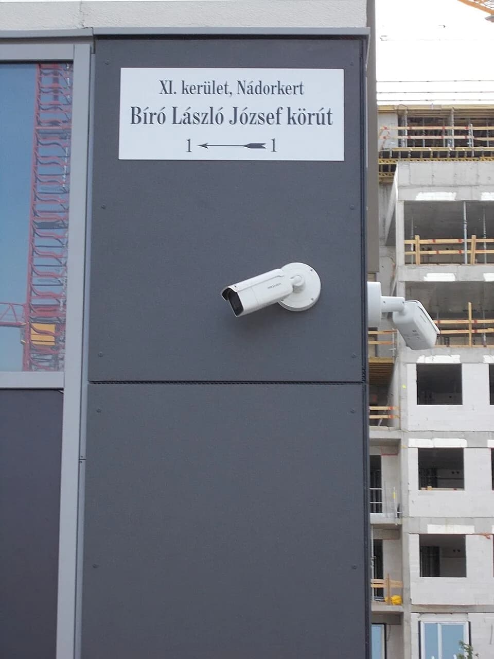 László Bíró - : Street name sign and CCTV cameras on the new Budapart (~Buda shore) Homes A building with circa 200 flats. #1 Bíró László József Boulevard in Nádorkert neighborhood, Budapest District 