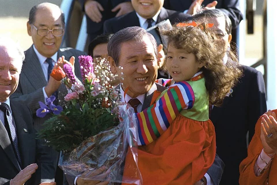 Roh Tae-woo - DF-SC-91-07853 President Roh Tae Woo of South Korea holds a child after accepting her bouquet of flowers upon his arrival on base.