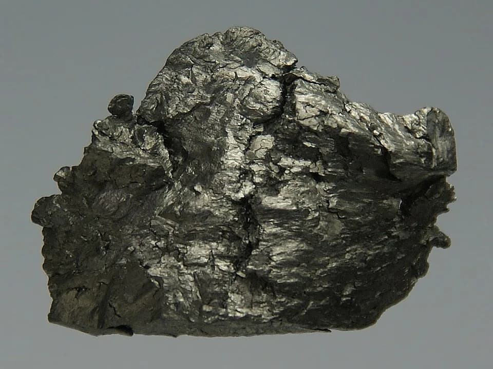 Johan Gadolin - Pure (99.95%) amorphous Gadolinium, about 12 grams, 2 × 1.5 × 0.5 cm, cast in acrylic glass.