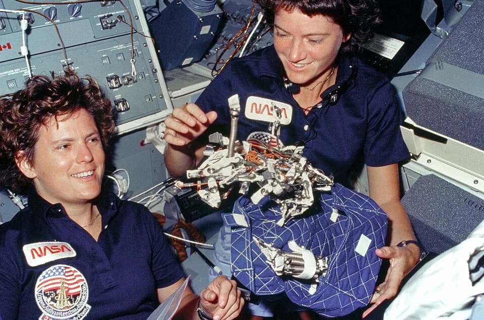 Sally Ride - Astronauts Kathryn D. Sullivan, left, and Sally K. Ride display a "bag of worms." The "bag" is a sleep restraint and the majority of the "worms" are springs and clips used with the sleep 