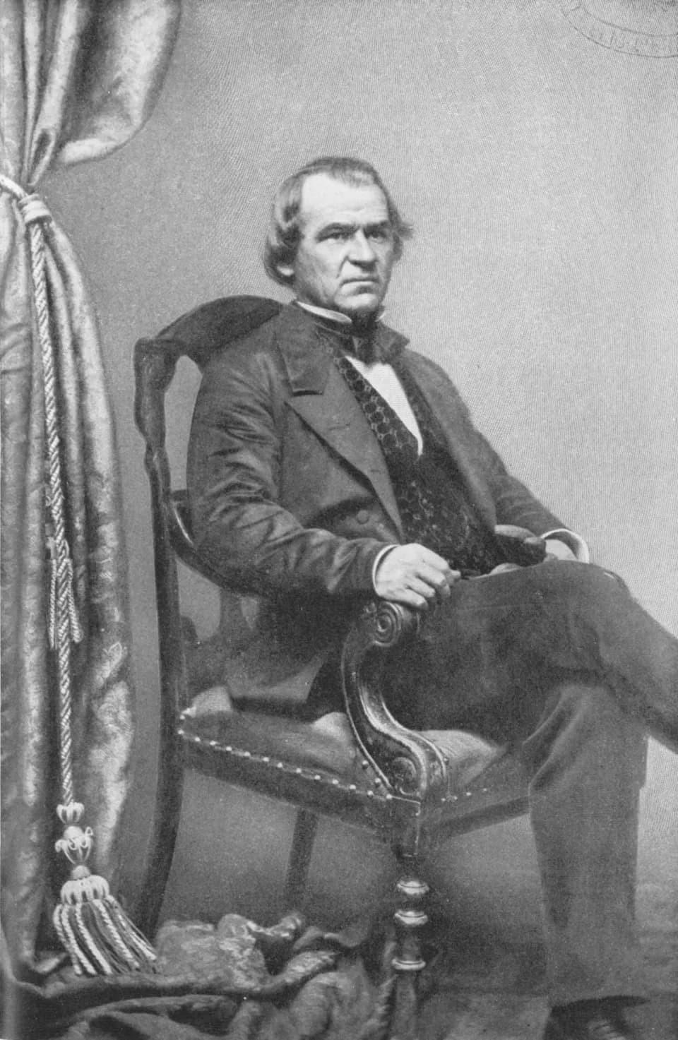 Andrew Johnson - Black-and-white photographic portrait of post-Civil-War U.S. President Andrew Johnson sitting in a chair.  It is almost a full shot though parts of his legs are clipped.
