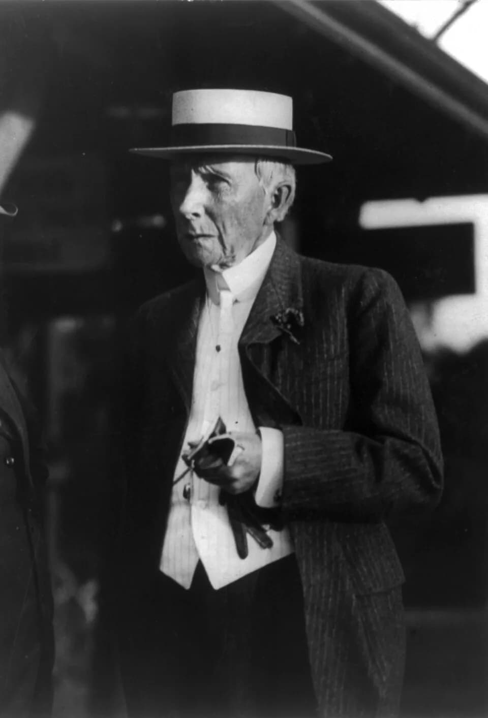 John D. Rockefeller - John D. Rockefeller, half-length portrait, standing, facing left, carrying gloves in his hand