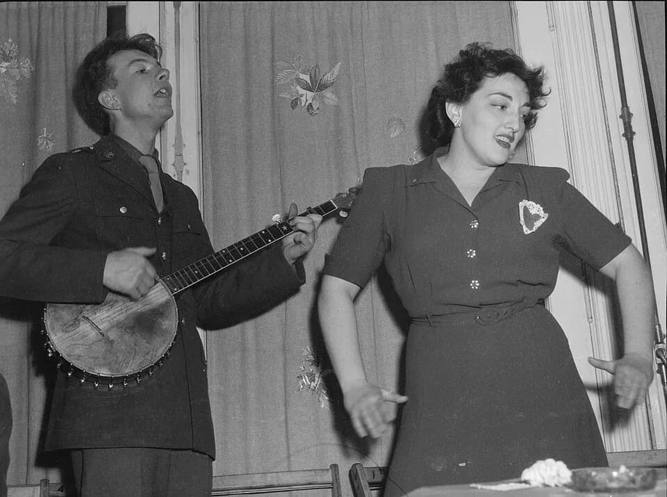 Pete Seeger - Pete Seeger (left), singing and playing banjo, for Valentine's Day party to mark the opening of the United Federal Labor Canteen, 1212 18th St. N.W., Washington, D.C., 1944. Unidentified