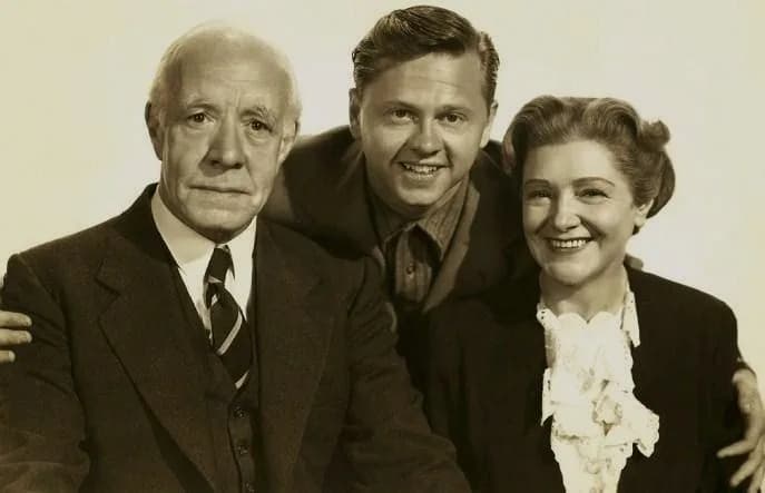 Mickey Rooney - L. to R. : Lewis Stone, Mickey Rooney & Fay Holden in Love Finds Andy Hardy - publicity still (original image damaged, modified and cropped : see source)