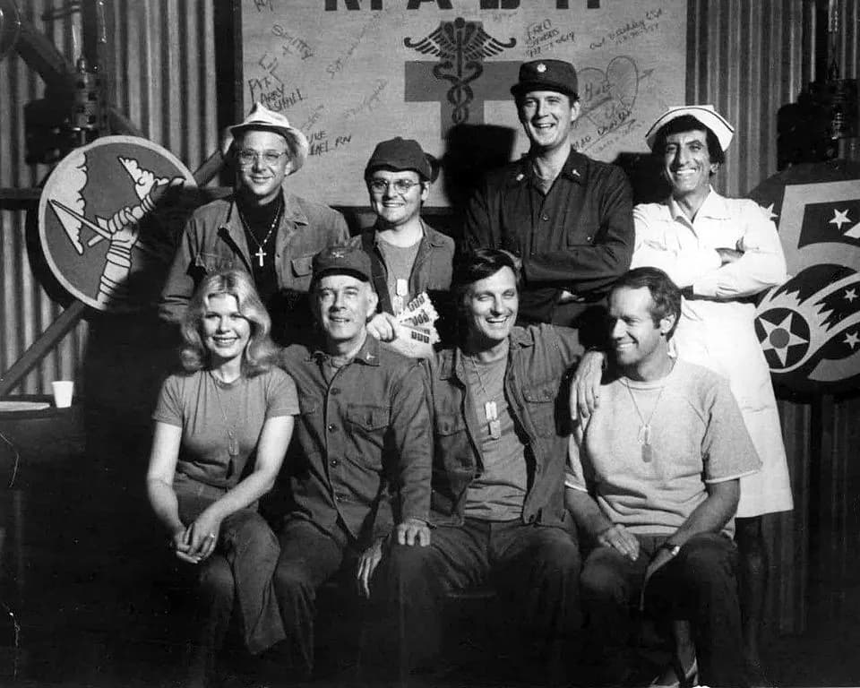 David Ogden Stiers - Cast photo from M*A*S*H for 1977.  Front row from left-Loretta Swit, Harry Morgan, Alan Alda, Mike Farrell.  Back row from left-William Christopher, Gary Burghoff, David Ogden Sti