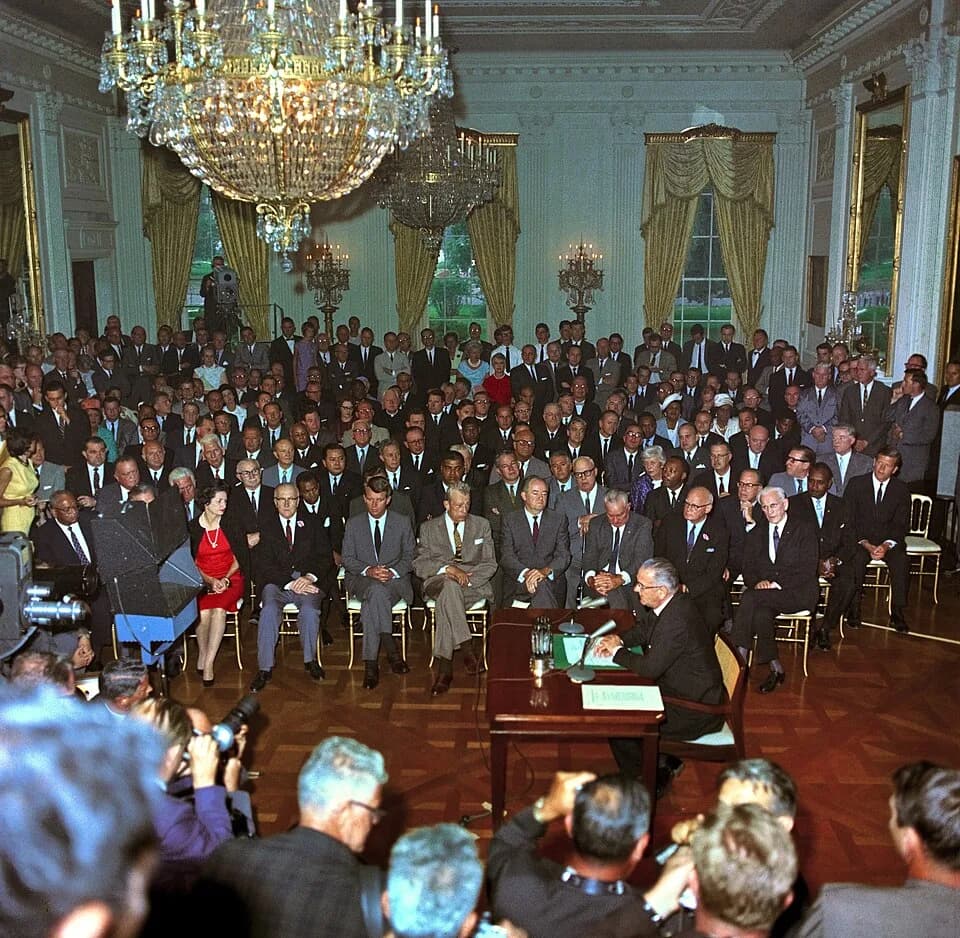 J. Edgar Hoover - President Lyndon B. Johnson at the signing the 1964 Civil Rights Act. White House East Room. People watching include Attorney General Robert Kennedy, Senator Hubert Humphrey, First L