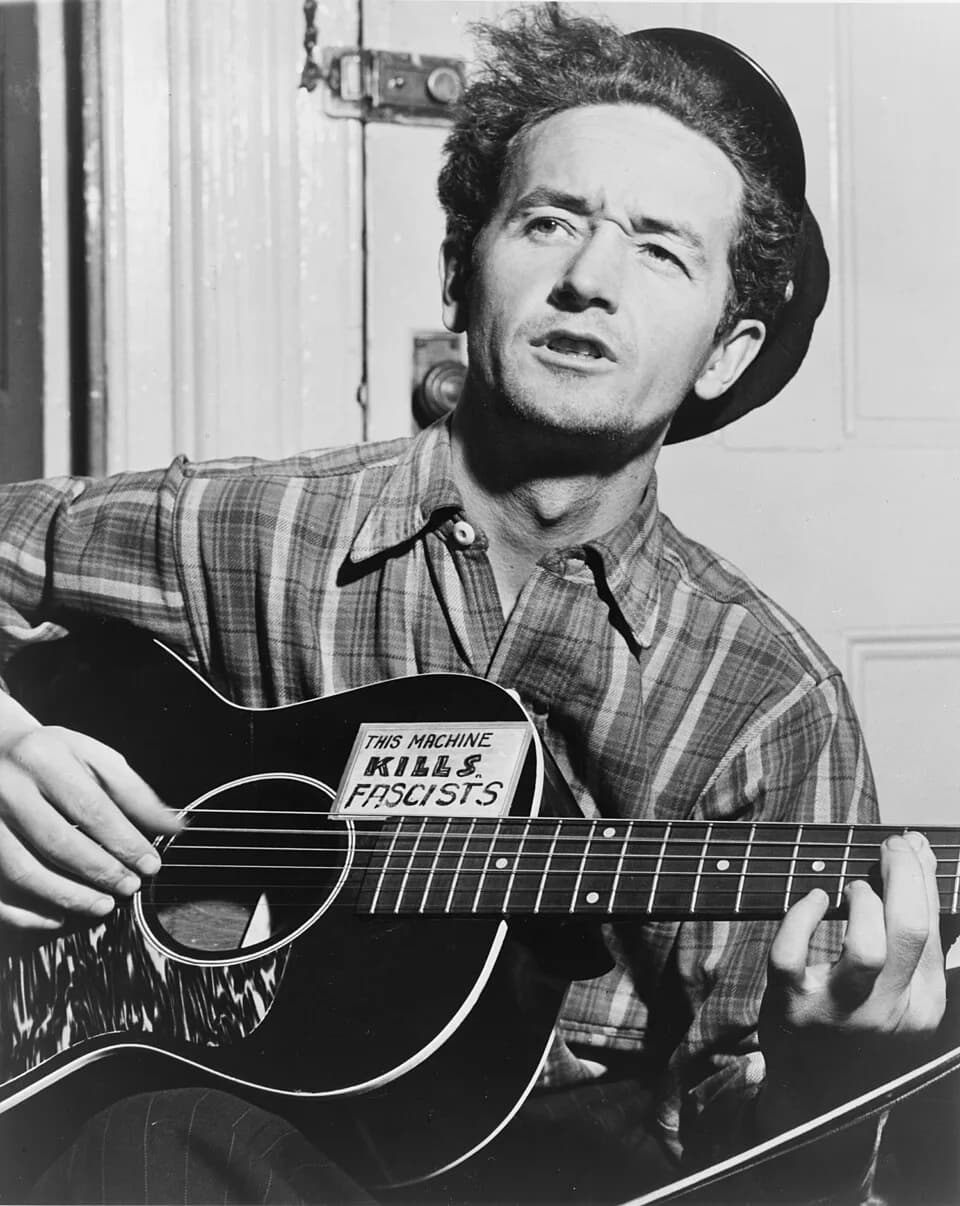 Woody Guthrie - Woody Guthrie, half-length portrait, facing slightly left, holding guitar / World Telegram photo by Al Aumuller.  
Gibson  L-0 (with bound back) — see more pictures of L-0, L-00, L-1, 
