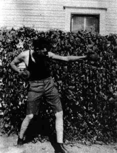 Robert E. Howard - Photograph of Robert E. Howard. Teenaged Robert E. Howard, posing with boxing gloves by the side of his home.