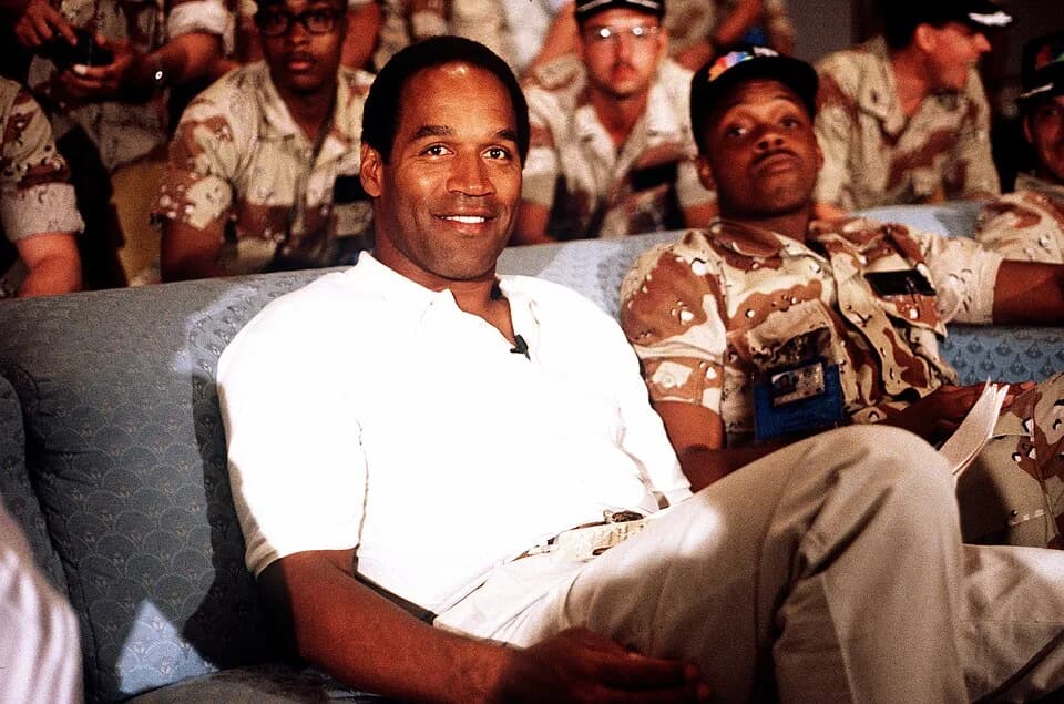 O. J. Simpson - NBC Sports commentator and former professional football player O. J. Simpson sits with a group of servicemen to watch a Thanksgiving Day football game. Simpson is visiting U.S. troops 