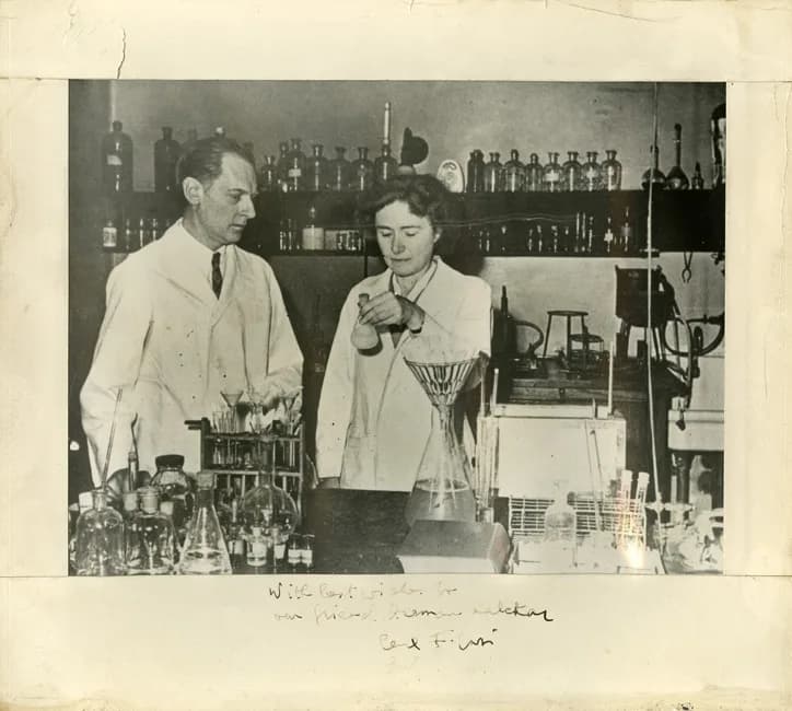 Carl Ferdinand Cori - Chemists Carl and Gerty Cori in the lab, autographed photo. Black and white photographed (adhered to cardstock).  Autographed by Carl Cori "With best wishes to our friend Herman 