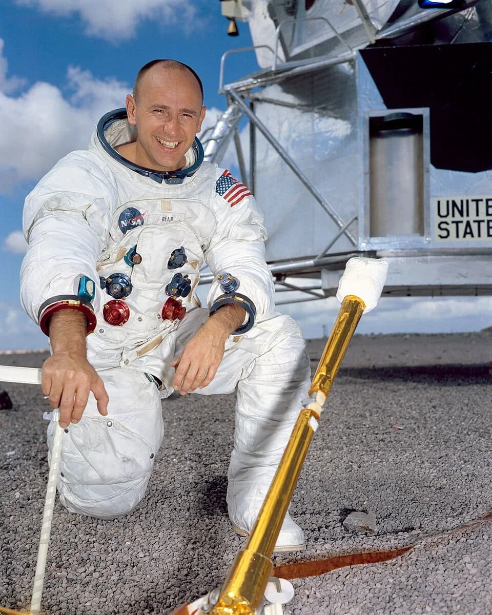 Alan Bean - Portrait of Astronaut Alan L. Bean, Prime Crew Lunar Module Pilot of the Apollo 12 Lunar Landing Mission, in his space suit minus the helmet. He is standing outside beside a mock-up of the