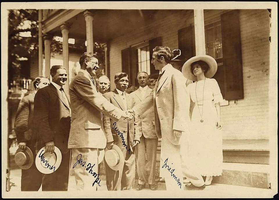 Jim Thorpe - Scope and content:  Jim Thorpe shaking hands with Moses Friedman while Glenn "Pop" Warner, Lewis Tewanima, and a crowd look on.