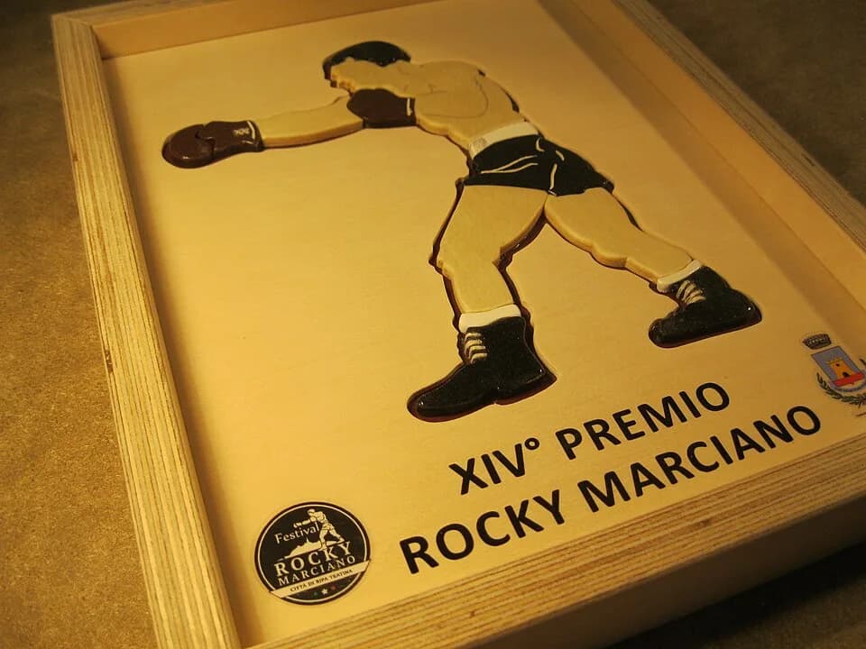 Rocky Marciano - Nel quadro in legno c'è un rilievo che raffigura una stilizzazione di Rocky Marciano (nella stessa posizione della statua presente a Ripa Teatina) con il logo del Premio in basso a si