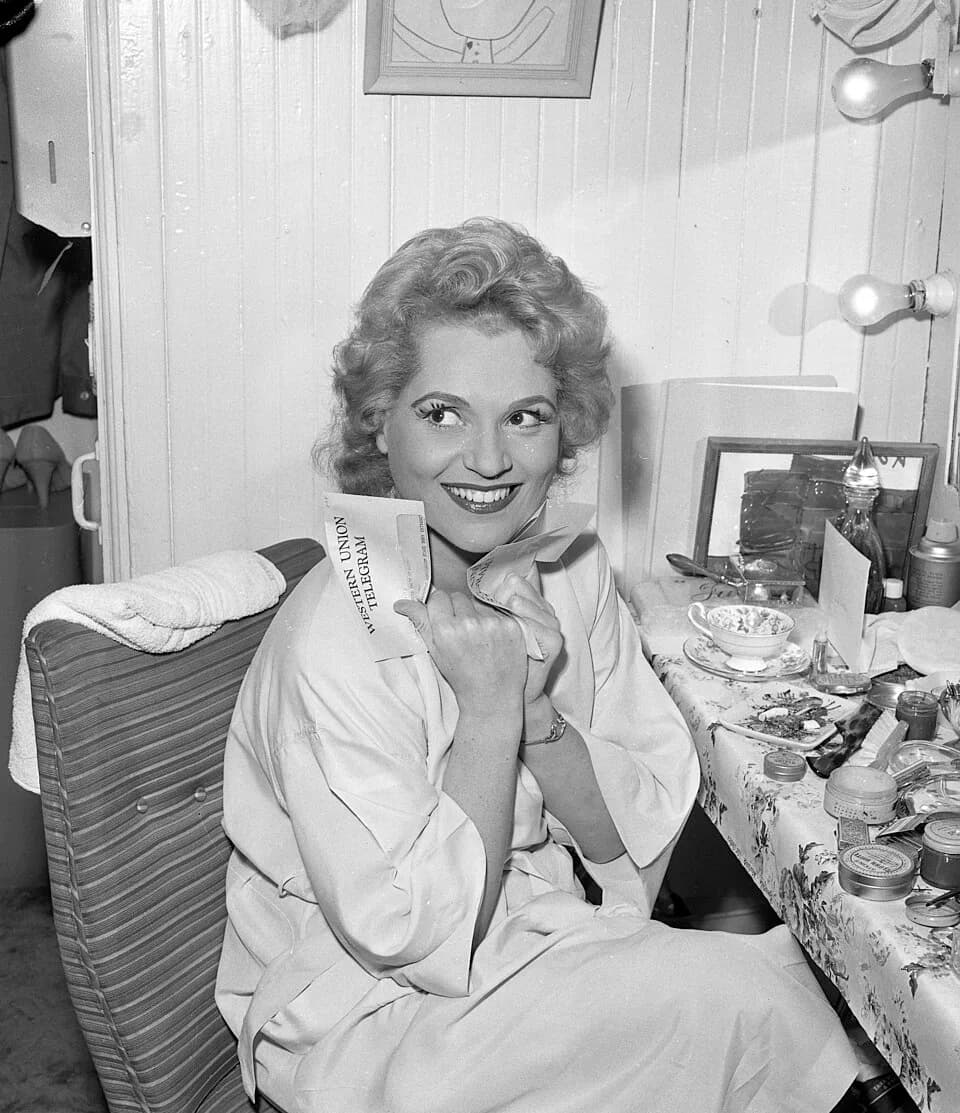 Judy Holliday - Actress Judy Holliday clutching a telegram in her dressing room before opening of the 22nd season of the Los Angeles Civic Light Opera.
Published caption:STAR OF MUSICAL-- Judy Hollida