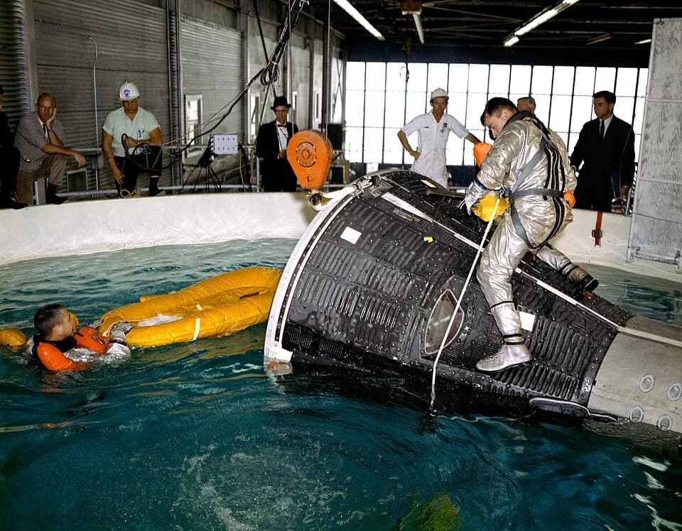 John Young - Astronauts John Young and Virgil I. (Gus) Grissom are pictured during water egress training in a large indoor pool at Ellington Air Force Base, Texas. Young is seated on top of the Gemini