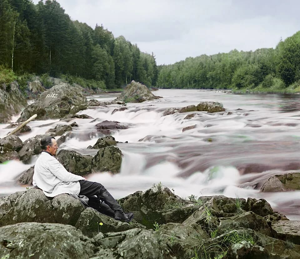 Sergei Prokudin-Gorskii - Original Description: Study near the Kivach waterfall. Suna River. Prokudin-Gorskii, reclined on boulders, near rapids. Prokudin-Gorsky's camera design required a camera oper
