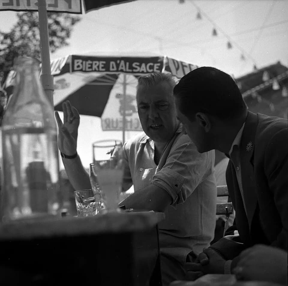 Jacques Tati - Noé (Haute-Garonne). 9 juillet 1961. Plan rapproché de deux personnes dont le réalisateur Jacques Tati en arrière plan, invité d'honneur de l'éléction de la "Belle Gaillarde".
Observati