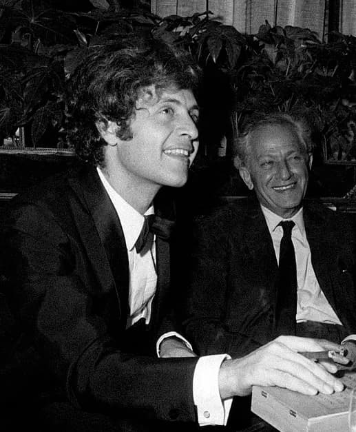 Joe Dassin - American-born French singer Joe Dassin smoking a cigar at the table of a bar. Beside him, his father, American director Jules Dassin. Paris, 1970.