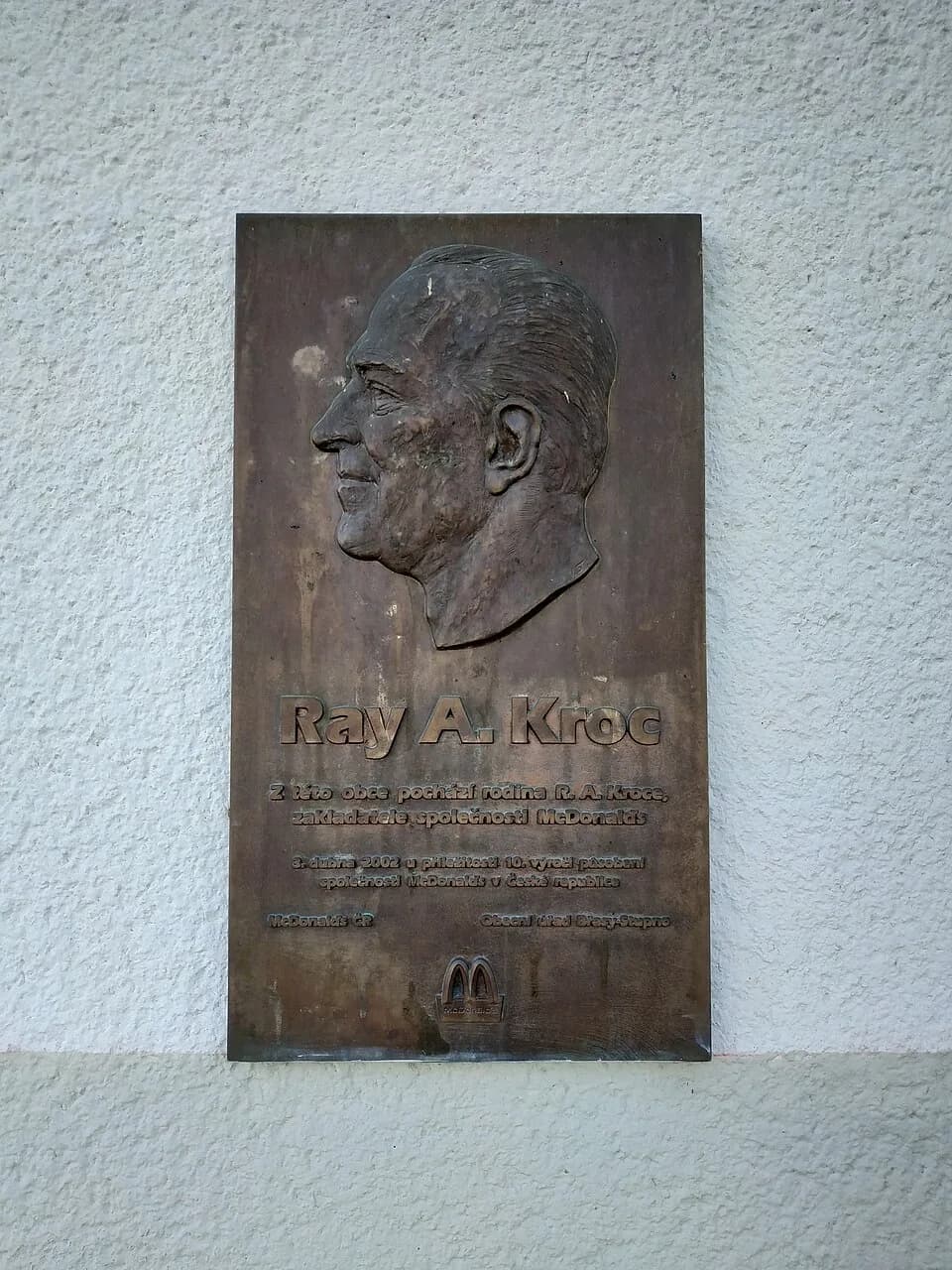 Ray Kroc - pamětní deska R. A. Kroce vedle vstupu prodejny Jednoty, Stupno čp. 181