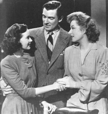 Teresa Wright - Teresa Wright with Walter Pidgeon and Greer Garson in a publicity still for the American film Mrs. Miniver (1942). Garson is wearing a costume designed by costume designer Robert Kallo