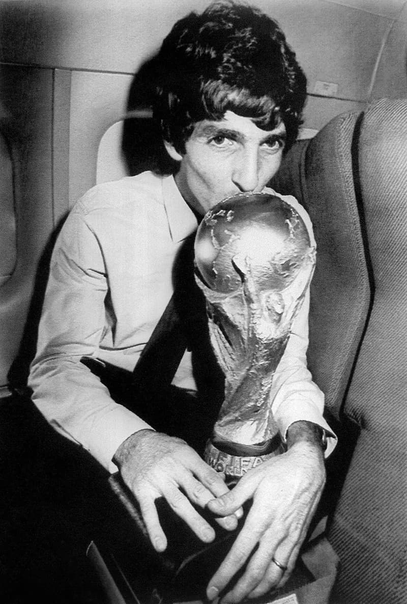 Paolo Rossi - Il calciatore dell'Italia, Paolo Rossi, sull'aereo del ritorno in patria dalla Spagna, bacia la Coppa del Mondo vinta dagli azzurri al campionato del mondo 1982; Rossi contribuì al terzo