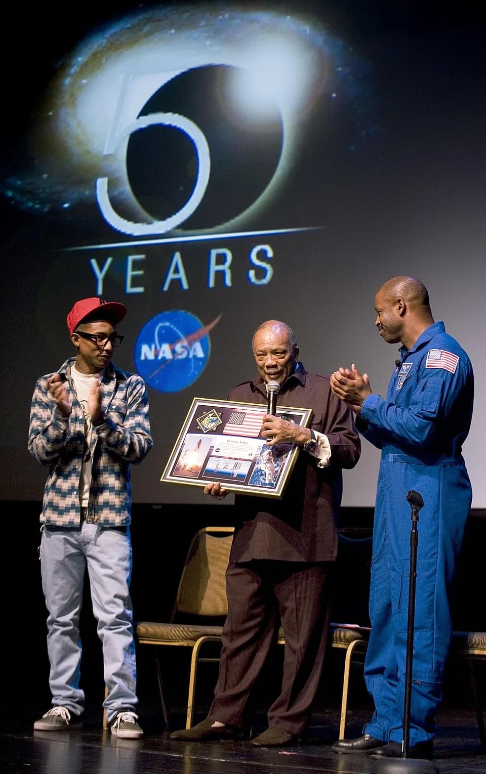 Quincy Jones - Music legend Quincy Jones, center, was presented with a montage by astronaut Leland Melvin, right, as hip-hop artist/producer Pharrell Williams looks on at a ceremony in Washington, D.C