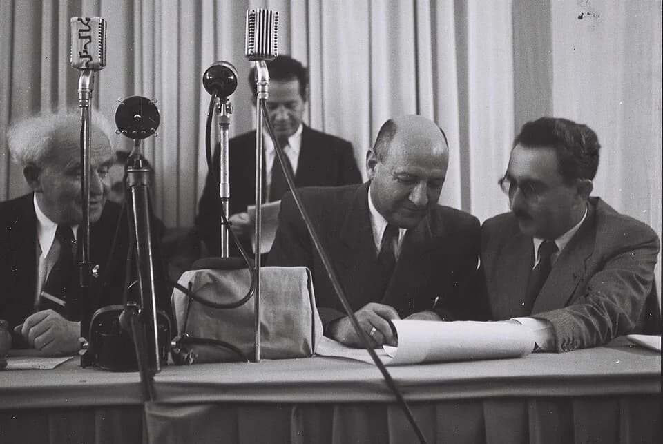 Moshe Sharett - Eliezer Kaplan signing the Declaration of Independence at The Tel Aviv Museum, with David Ben Gurion and Moshe Shertok sitting next to him and Ze'ev Sherf standing behind