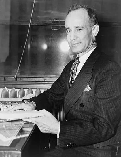 Napoleon Hill - Napoleon Hill, American self-help writer, attorney and journalist, seated in a chair holding his book "Think and Grow Rich". (three-quarter length portrait)