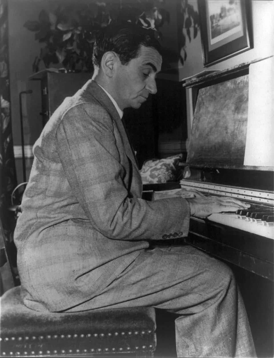 Irving Berlin - Jewish immigrant Irving Berlin, pictured in 1948. Portrait, seated at piano, profile, facing right. Gift of Irving Lowens, 1966.