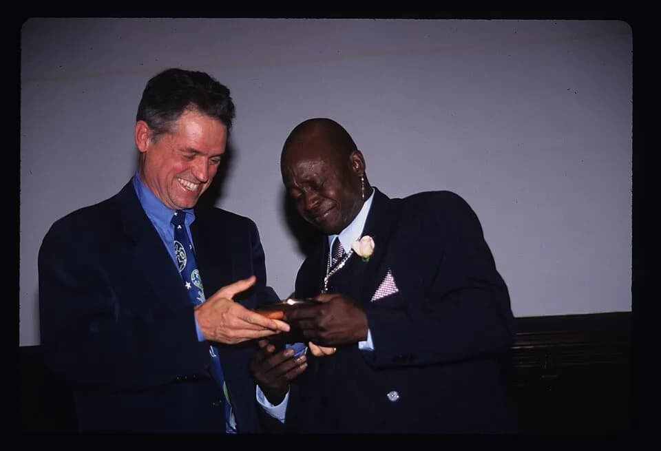 Jonathan Demme - This photograph shows filmmaker Jonathan Demme (left) presenting Master Drummer Frisner Augustin with an award from the cultural center City Lore at its People's Hall of Fame award ce
